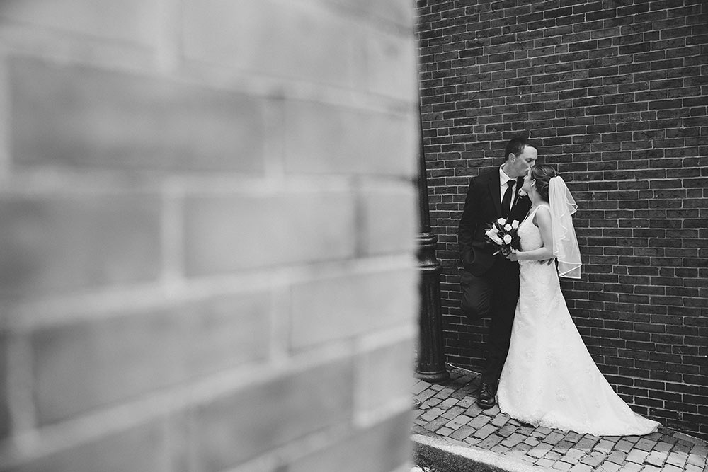 A documentary photograph of a couple sharing a kiss during their wedding portrait session in Beacon Hill