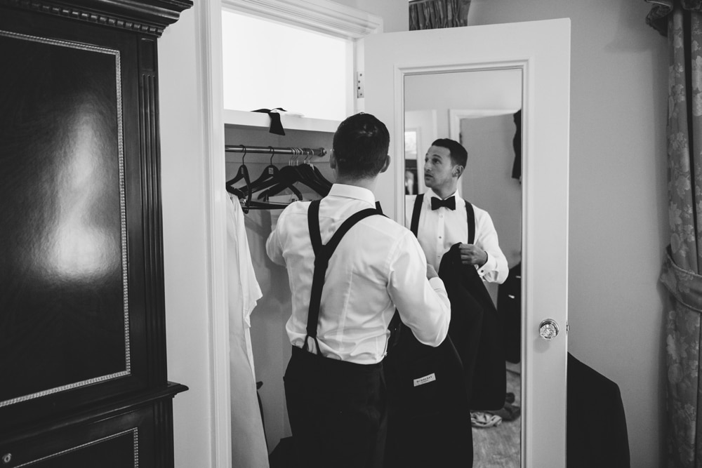 A documentary photograph of a Groomsman getting his tuxedo jacket from the closet before his Taj Boston Hotel Wedding in the Back Bay