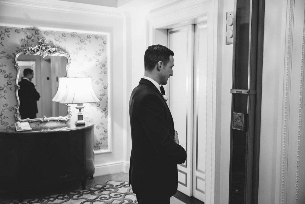 A documentary photograph of a Groomsman waiting for his elevator to arrive before he can meet his bride at the First Look before their Taj Boston Hotel Wedding