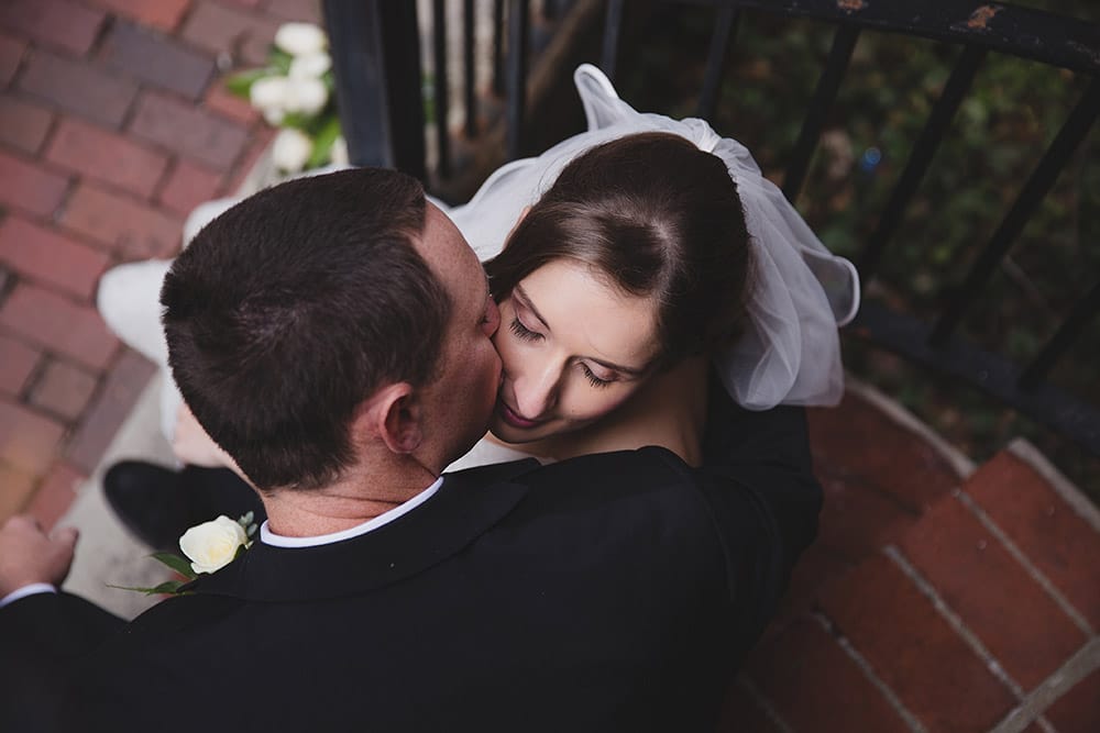 An artistic photograph of a groom kissing his bride during their wedding portrait session in Beacon Hill