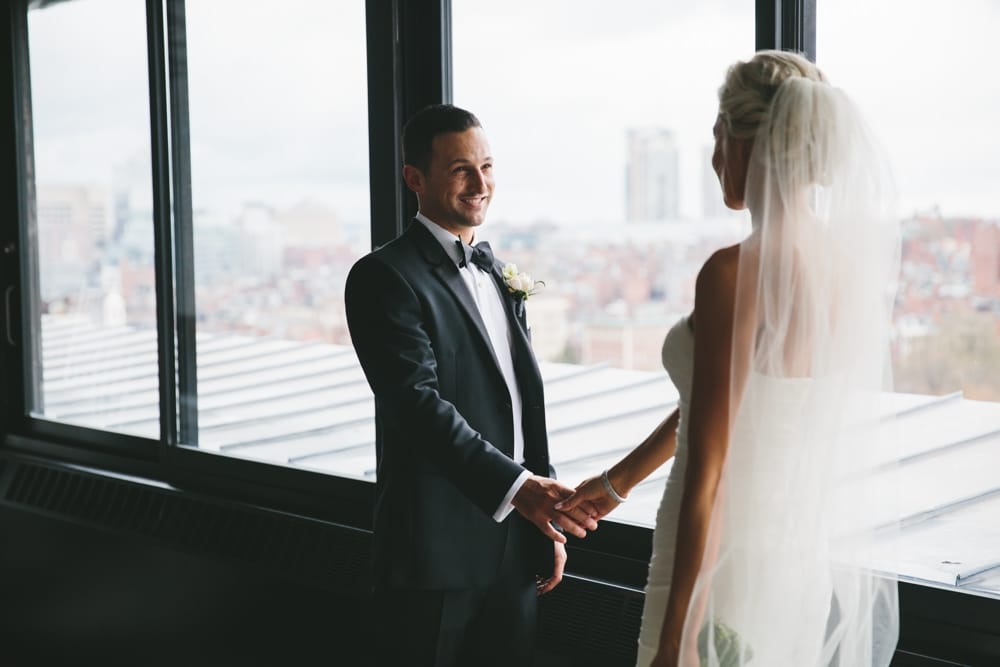 A documentary portrait of a bride and groom holding hands during their first look at a Taj Boston Hotel Wedding