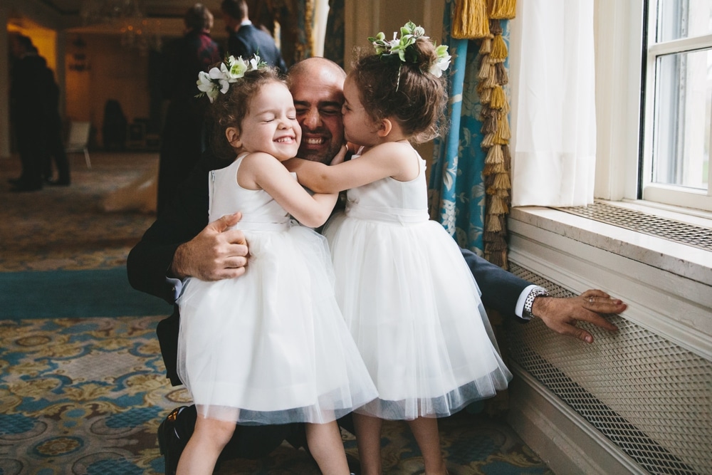 A documentary photograph of twin flower girls hugging their dad during a Taj Boston Hotel Wedding in Massachusetts