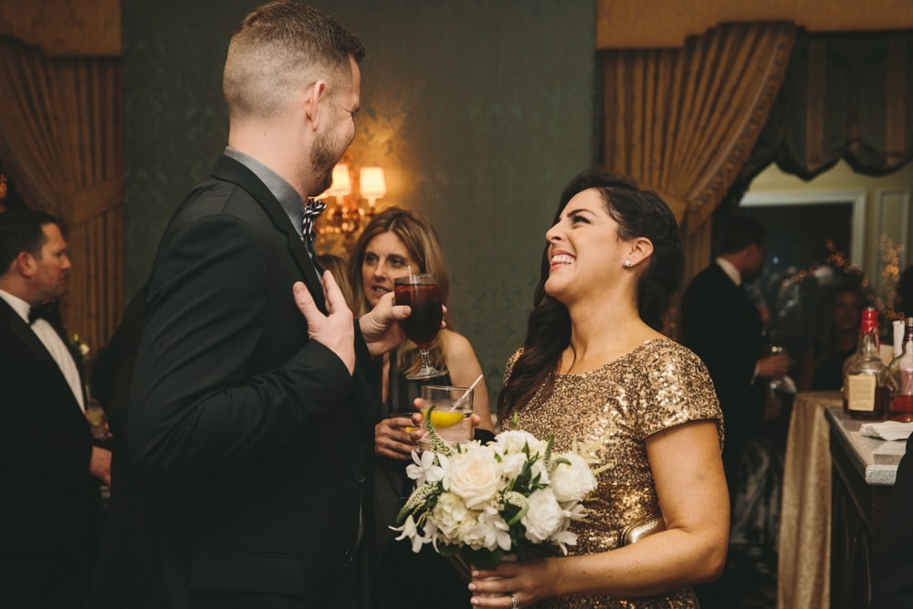 A documentary photograph of a bridesmaid laughing with guest during the cocktail hour of a Taj Boston Hotel Wedding in Massachusetts