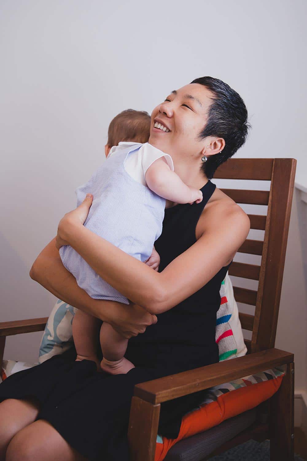 A lifestyle photograph showing everyday motherhood as a mother hugs her baby boy during an in home family session in Jamaica Plain, Boston