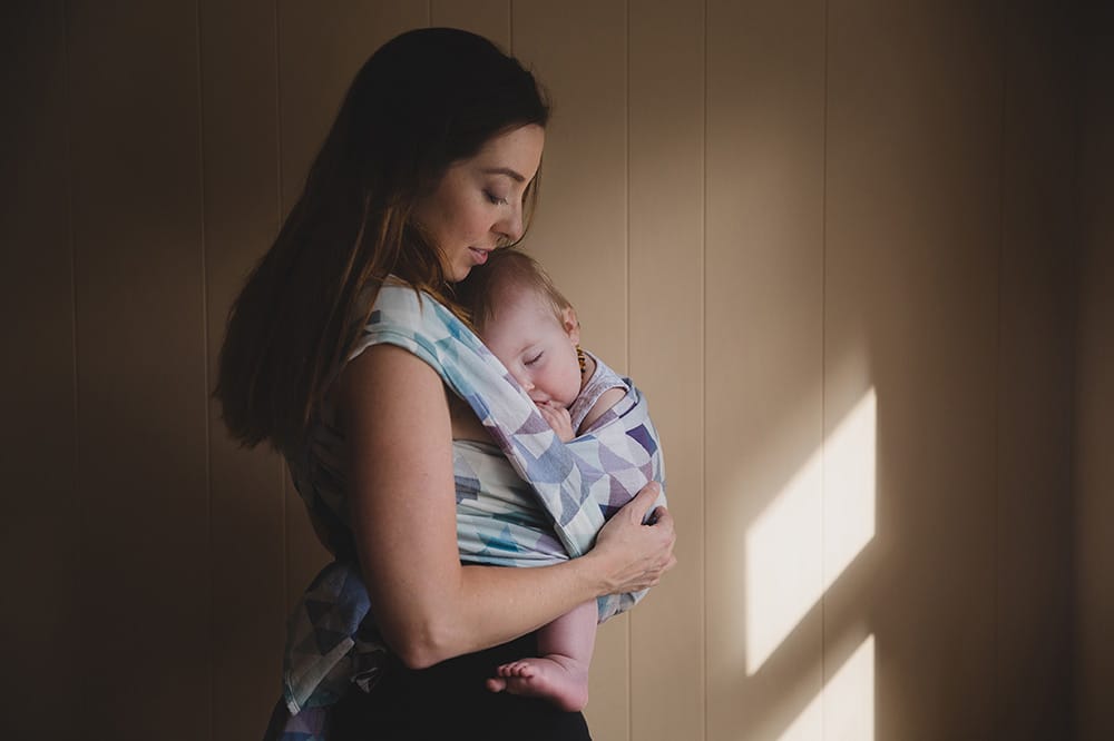 A lifestyle photograph showing beautiful everyday motherhood as a mom nurses her baby girl during an in home family session in Boston
