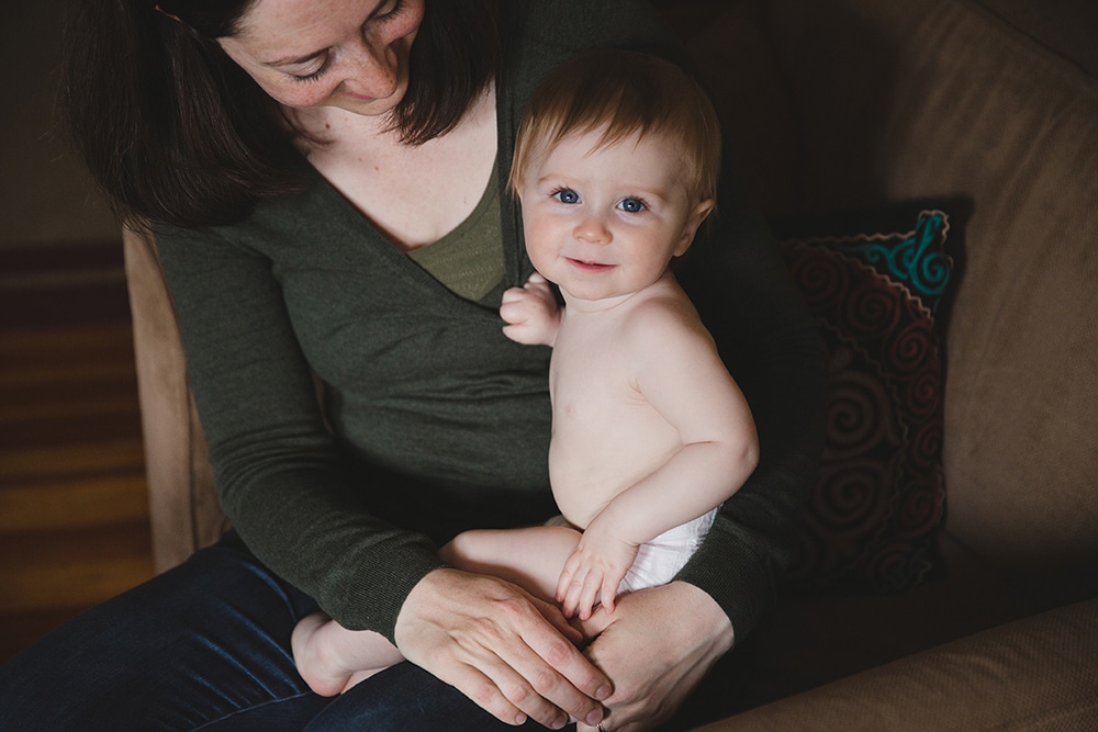 A lifestyle photograph of a mother holding her son before he gets dressed during a family session at home in Boston, Massachusetts