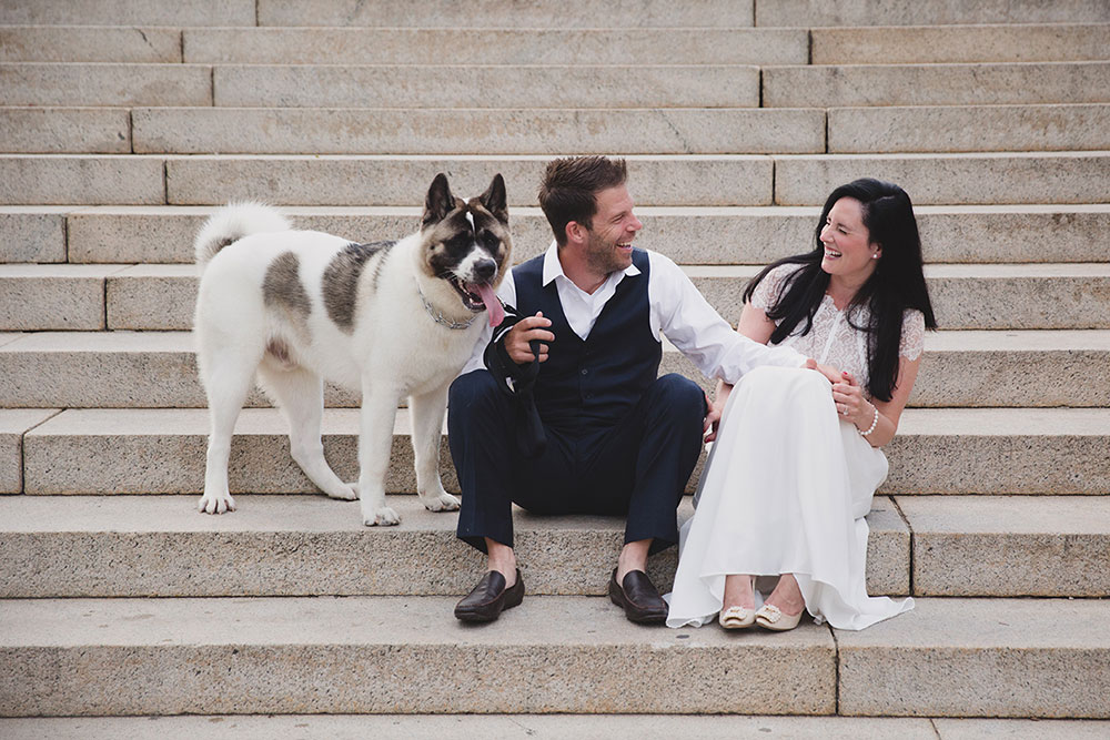 A documentary photograph of a couple laughing on the steps of the Boston Common during their Boston Engagement Session