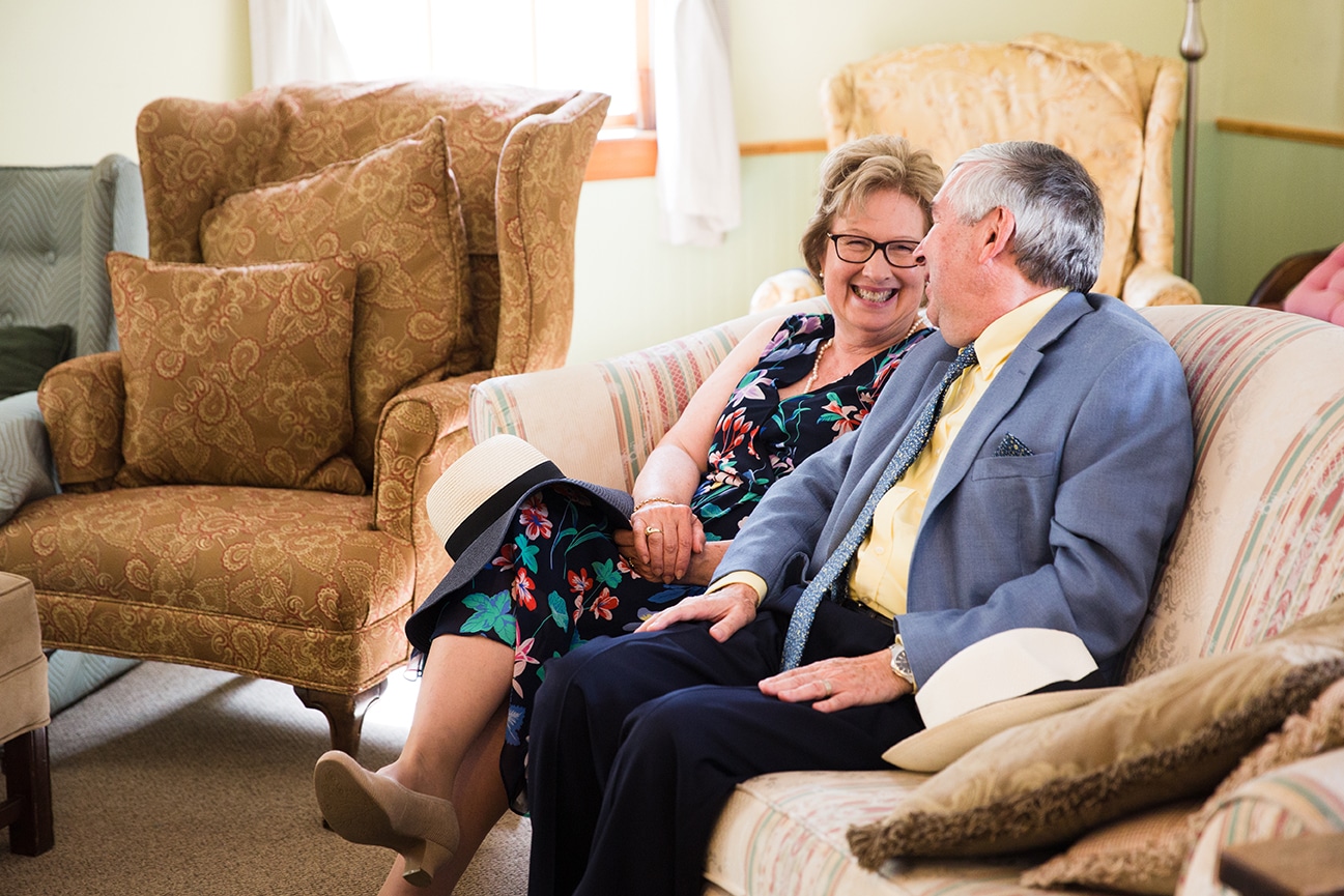 A documentary photograph of the bride's parents laughing before their daughter's Friendly Crossways Wedding