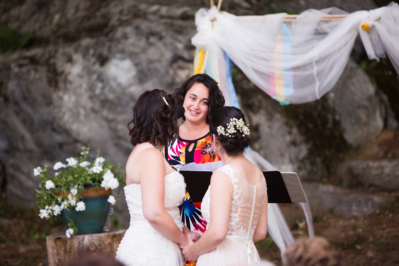 A documentary photograph of two brides during their outdoor ceremony at Friendly Crossways Wedding venue