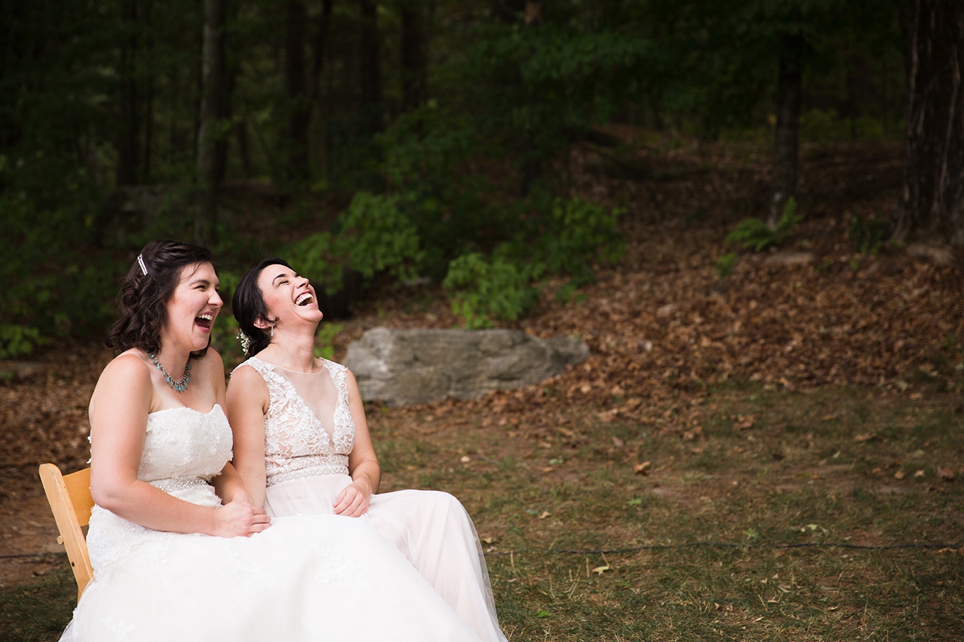 A documentary photograph of two brides laughing during their outdoor wedding ceremony at Friendly Crossways Wedding venue