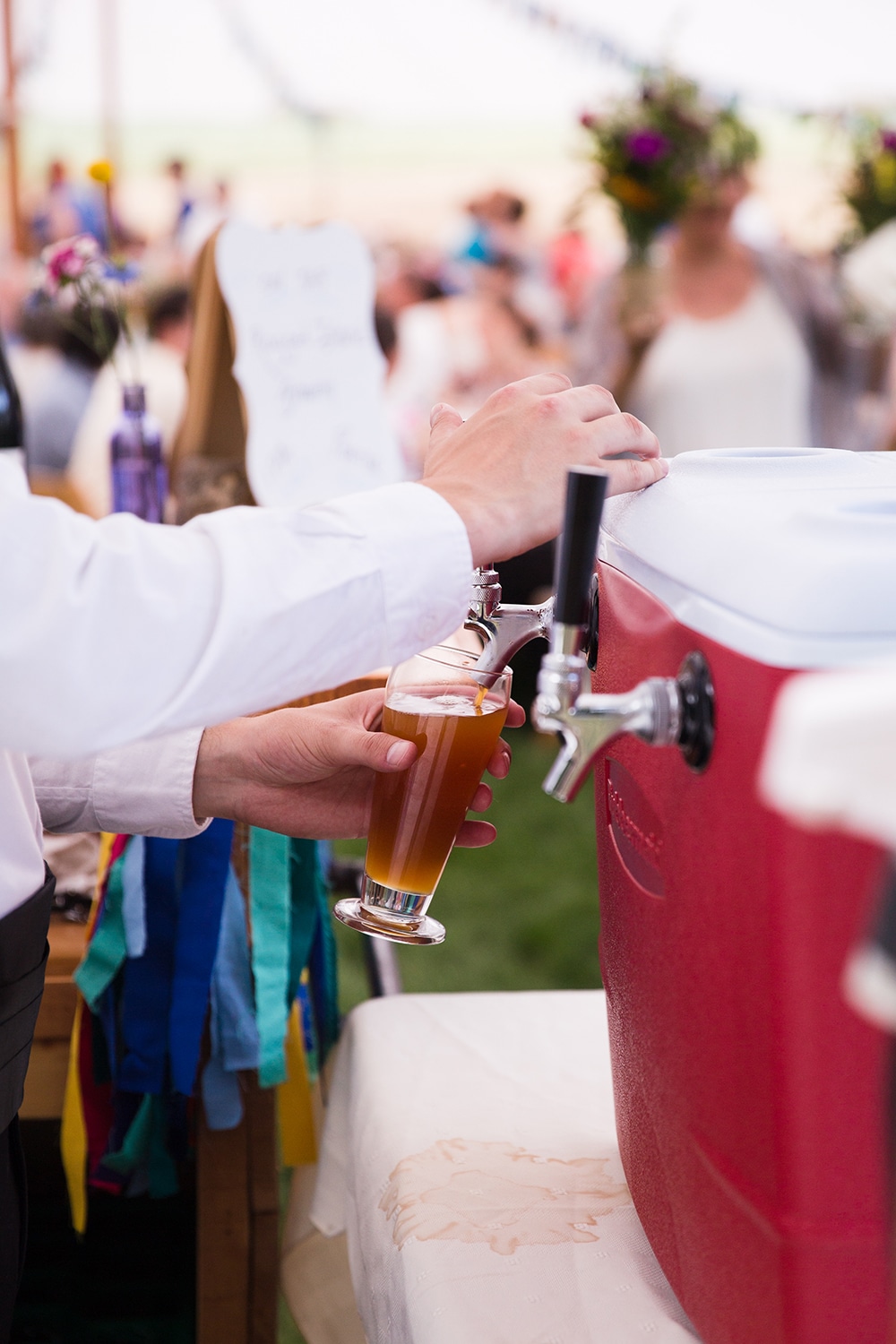 A documentary photograph of a guest pouring craft beer at a Friendly Crossways Wedding