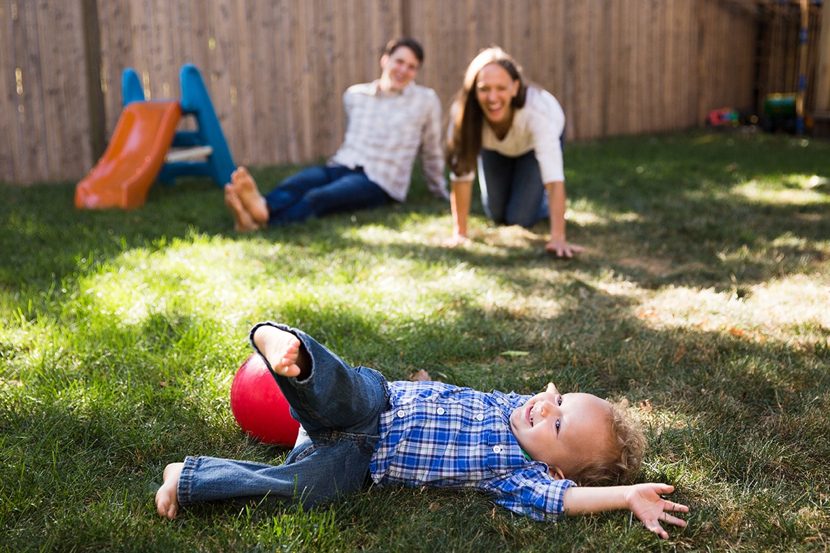 A lifestyle photograph of a family playing in their yard during an in home family session in Boston