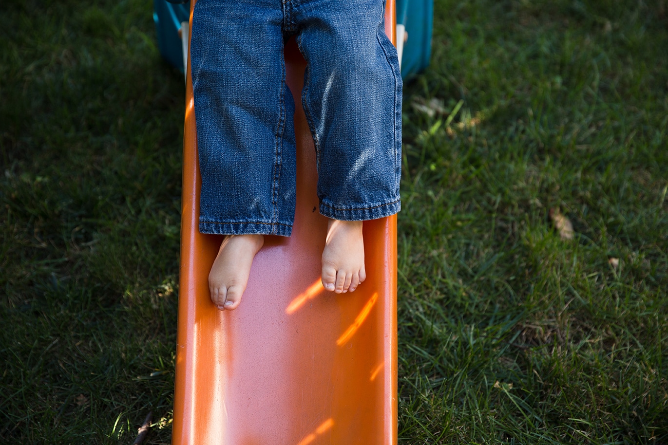 A lifestyle photograph of a toddler sliding down his slide during an in home family session in Boston