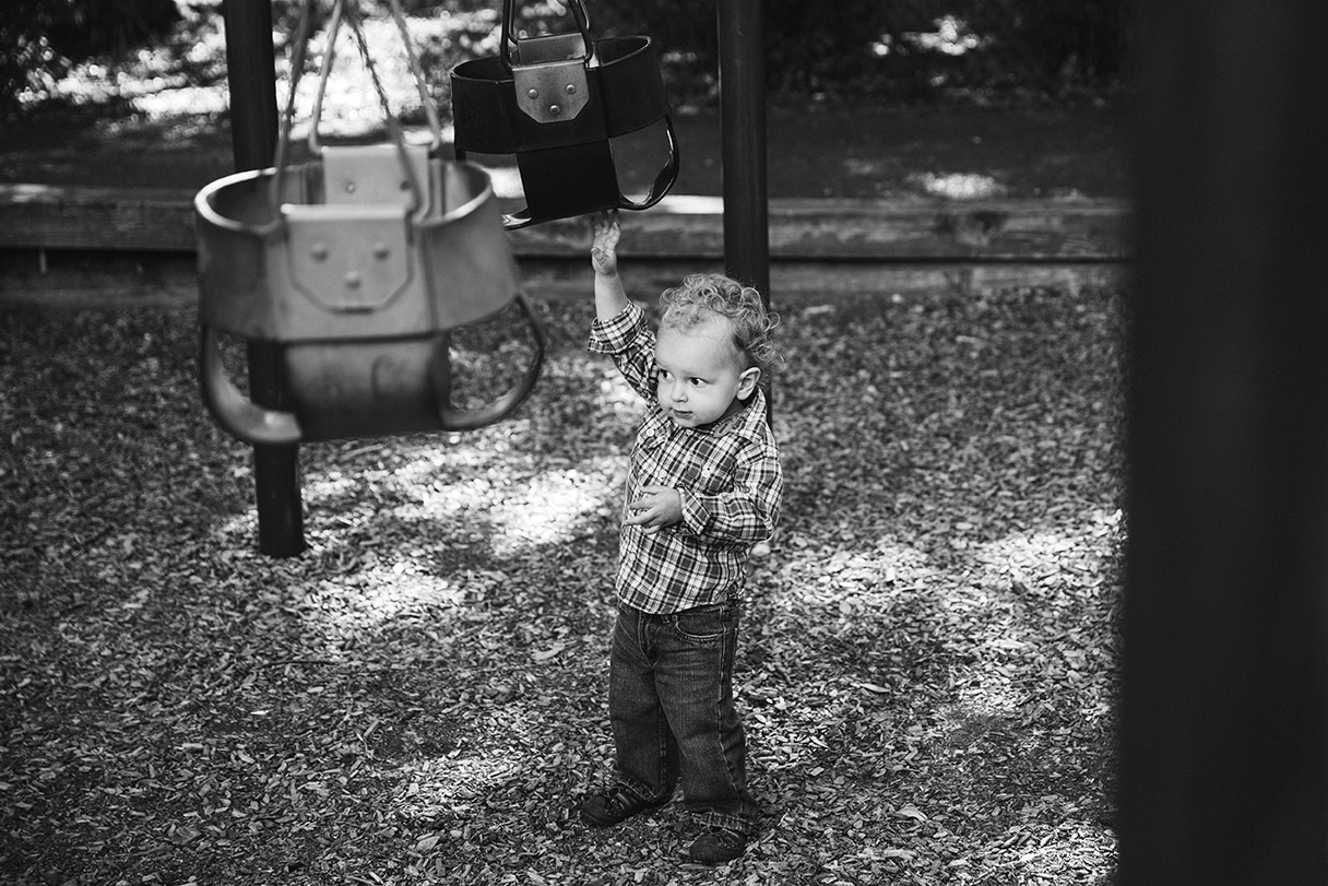 A documentary photograph of toddler holding a swing during an in home family session in Boston