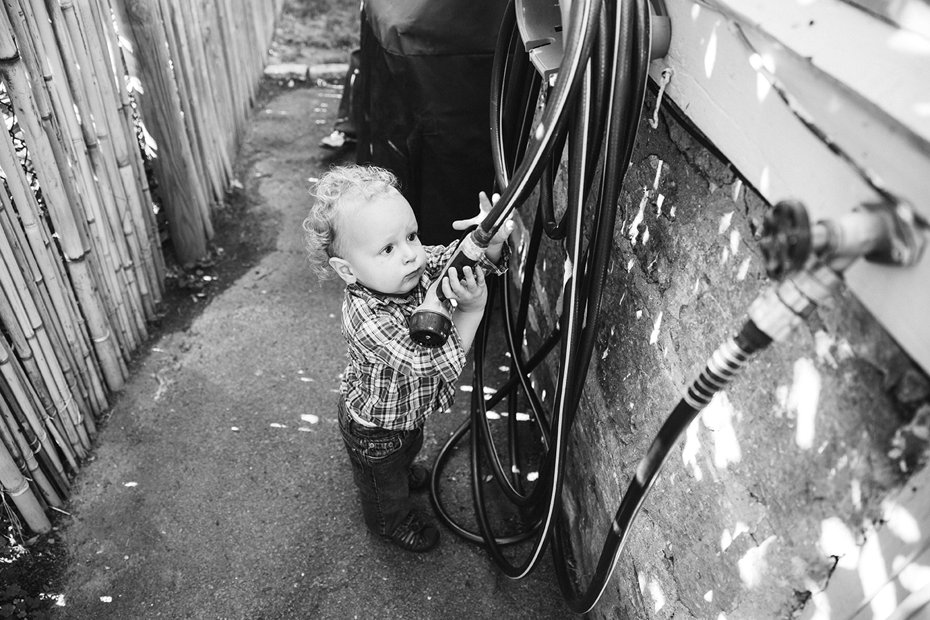 A lifestyle photograph of boy grabbing the hose during an in home family session in Boston