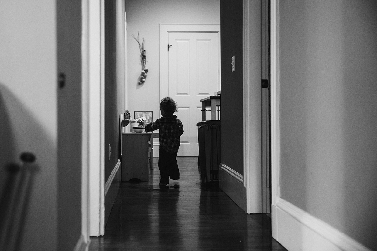 A lifestyle photograph of a boy playing in the kitchen during an in home family session in Boston
