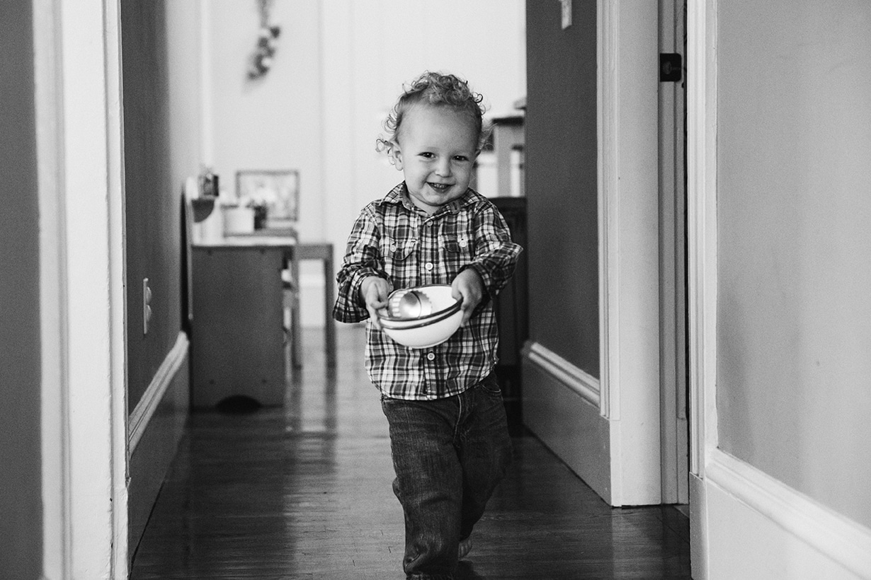 A lifestyle photograph of boy carrying his toys during an in home family session in Boston