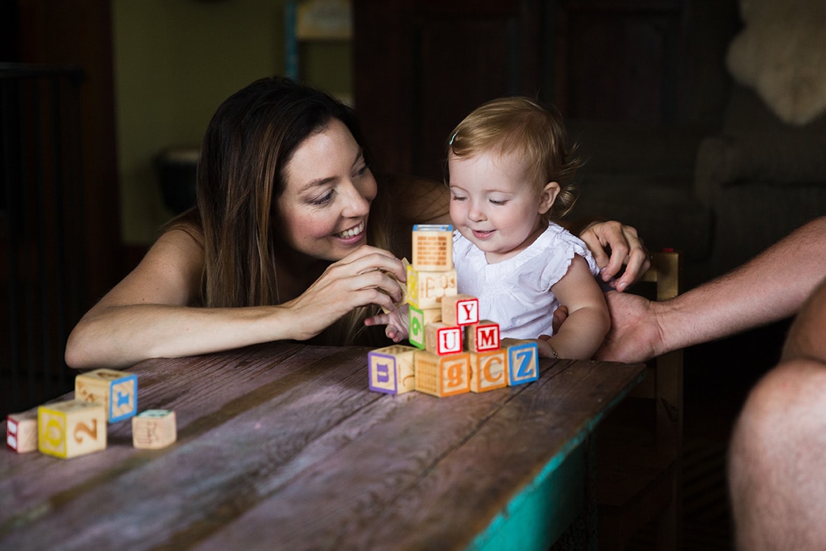 A lifestyle photograph of a mom stacking blocks with her daughter during a evergreen family session at their home in Colorado