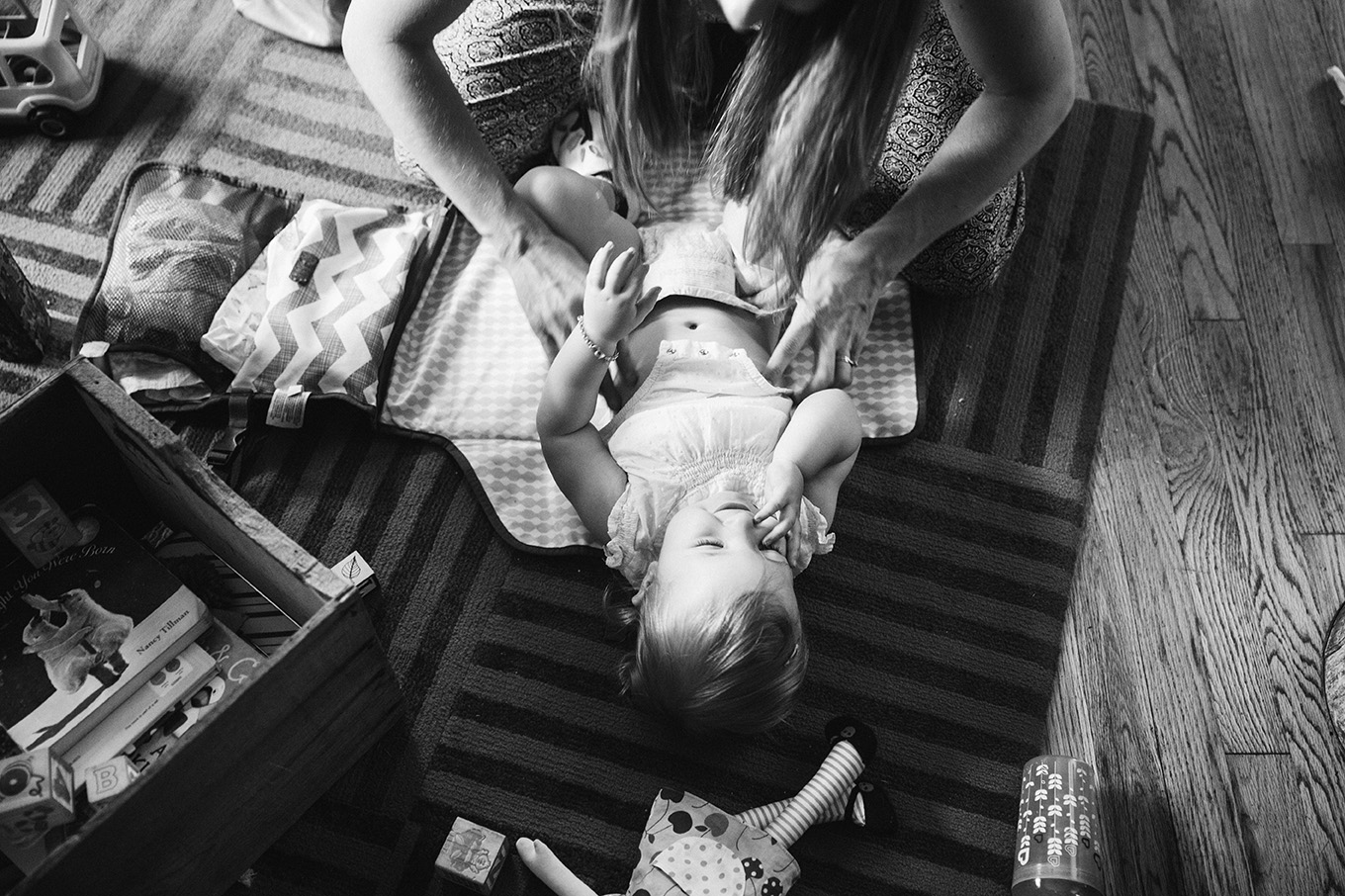 A documentary photograph of a mom changing her daughter's diaper during their evergreen family session at home in Colorado