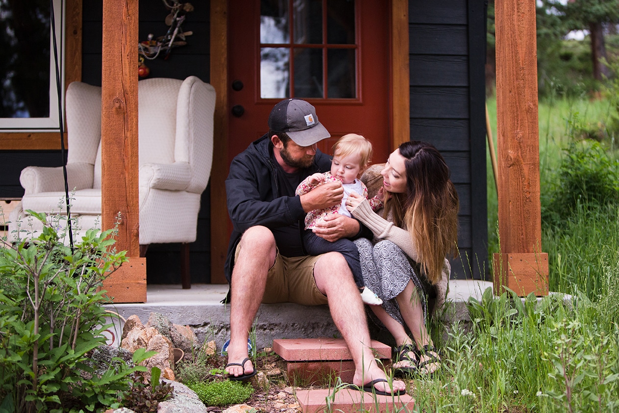 A lifestyle photograph of a family sitting on their porch during an evergreen family photo session in Colorado
