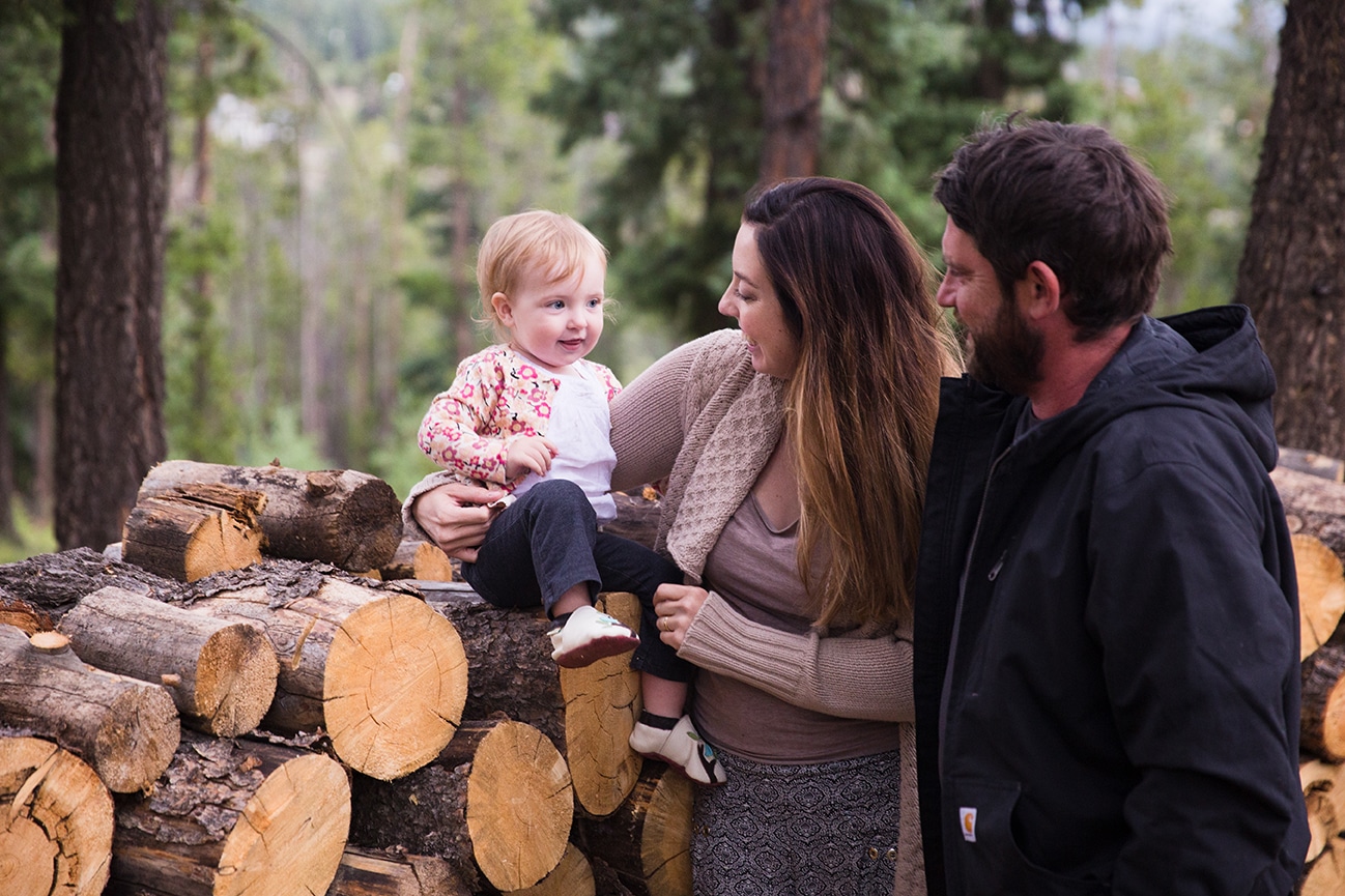 A lifestyle photograph of a family near their wood pile during a family session at home in Colorado