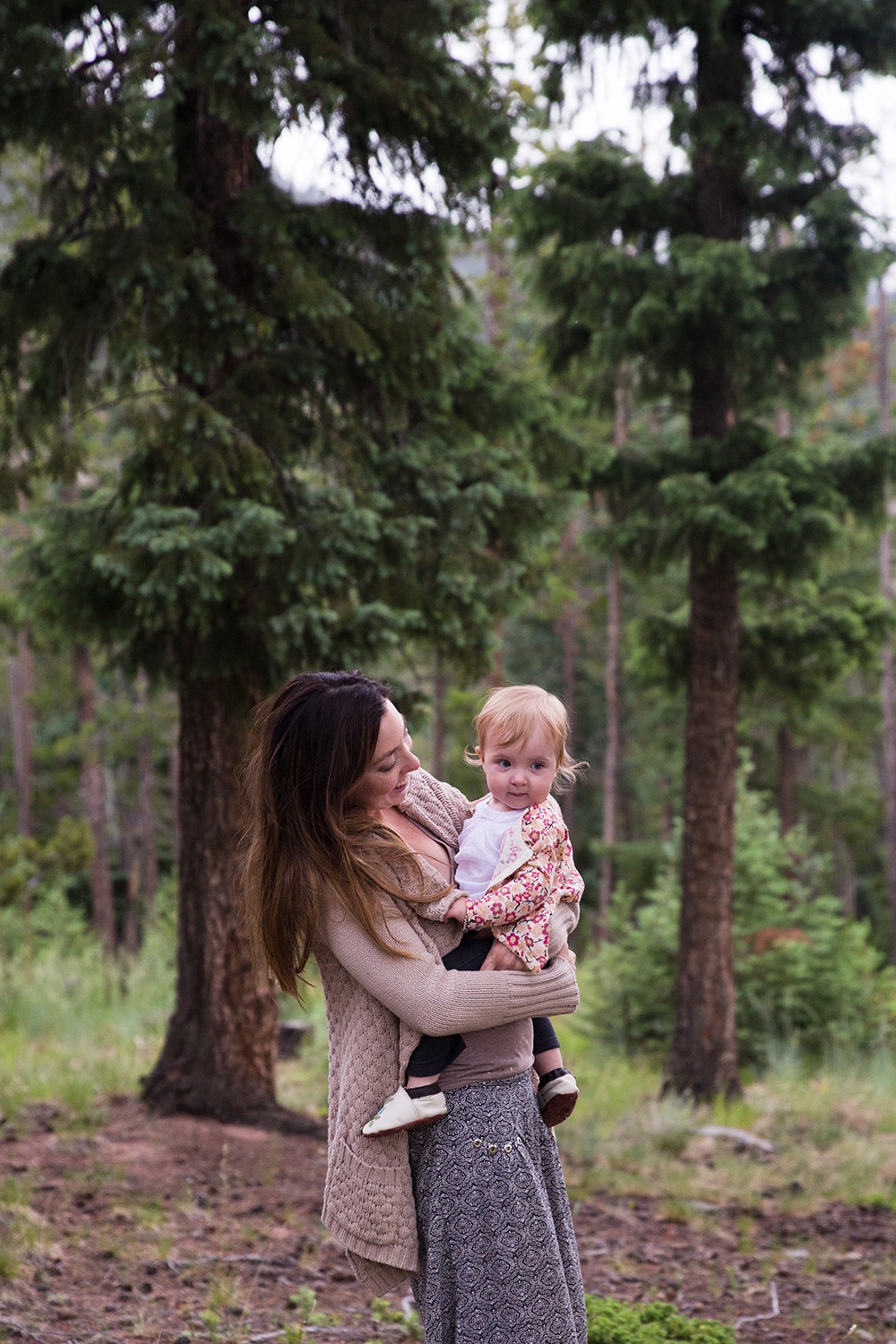 A lifestyle portrait of a mom holding her daughter during an evergreen family session in Colorado