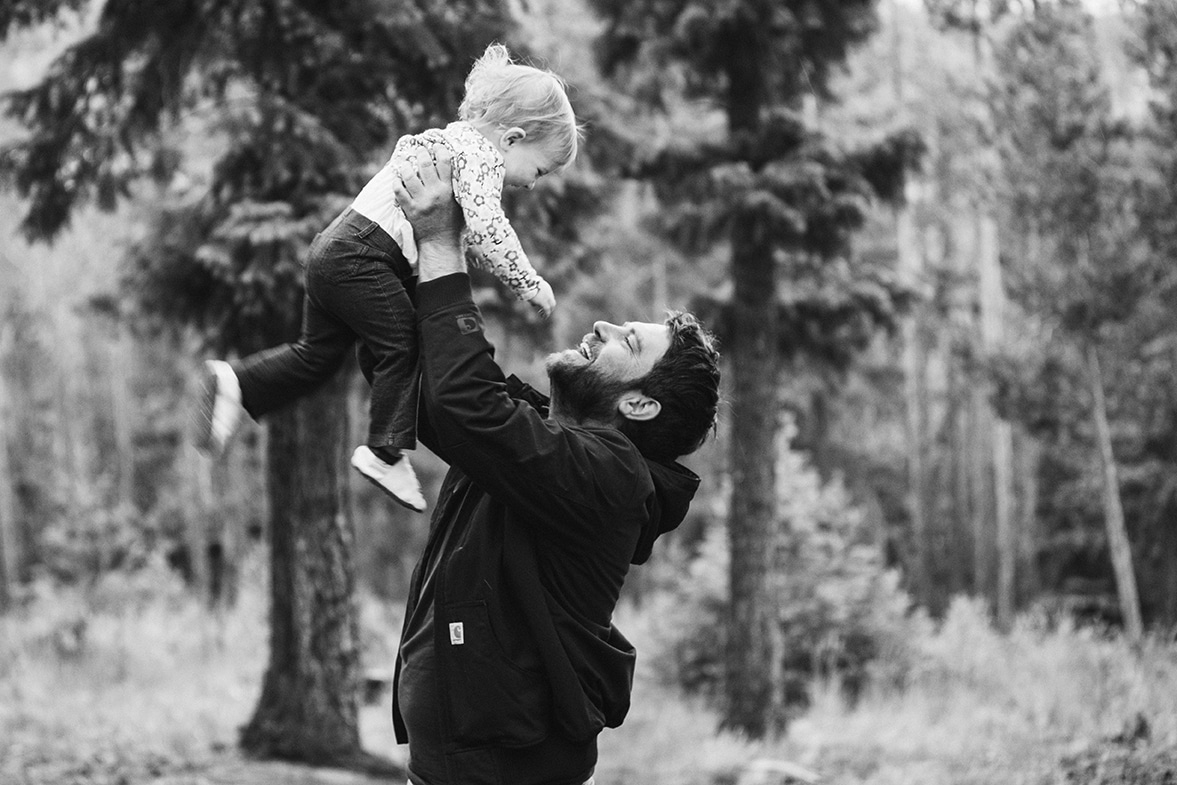 A documentary photograph of dad playing with his daughter during their evergreen family session in Colorado