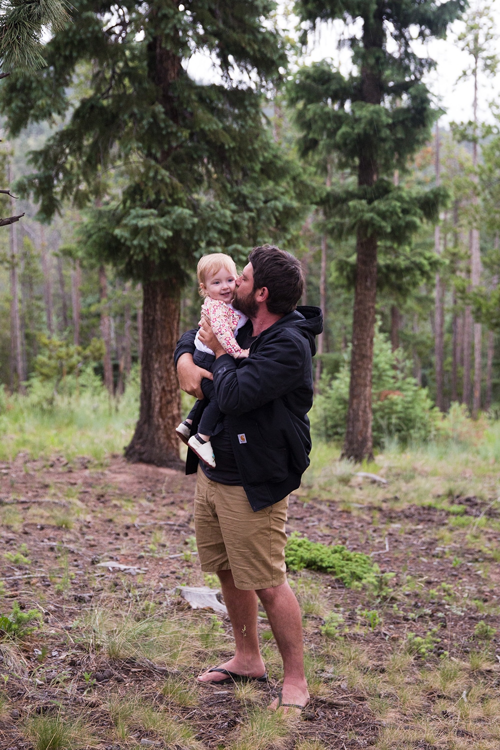 A lifestyle photograph of a dad holding his daughter during an evergreen family session in Colorado