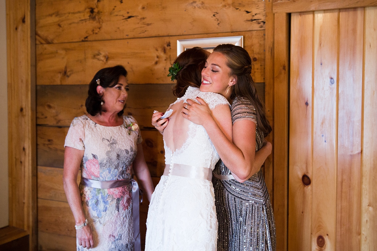 A documentary photograph of a bride hugging her sister before her Kingsley Pines Camp Wedding in Maine