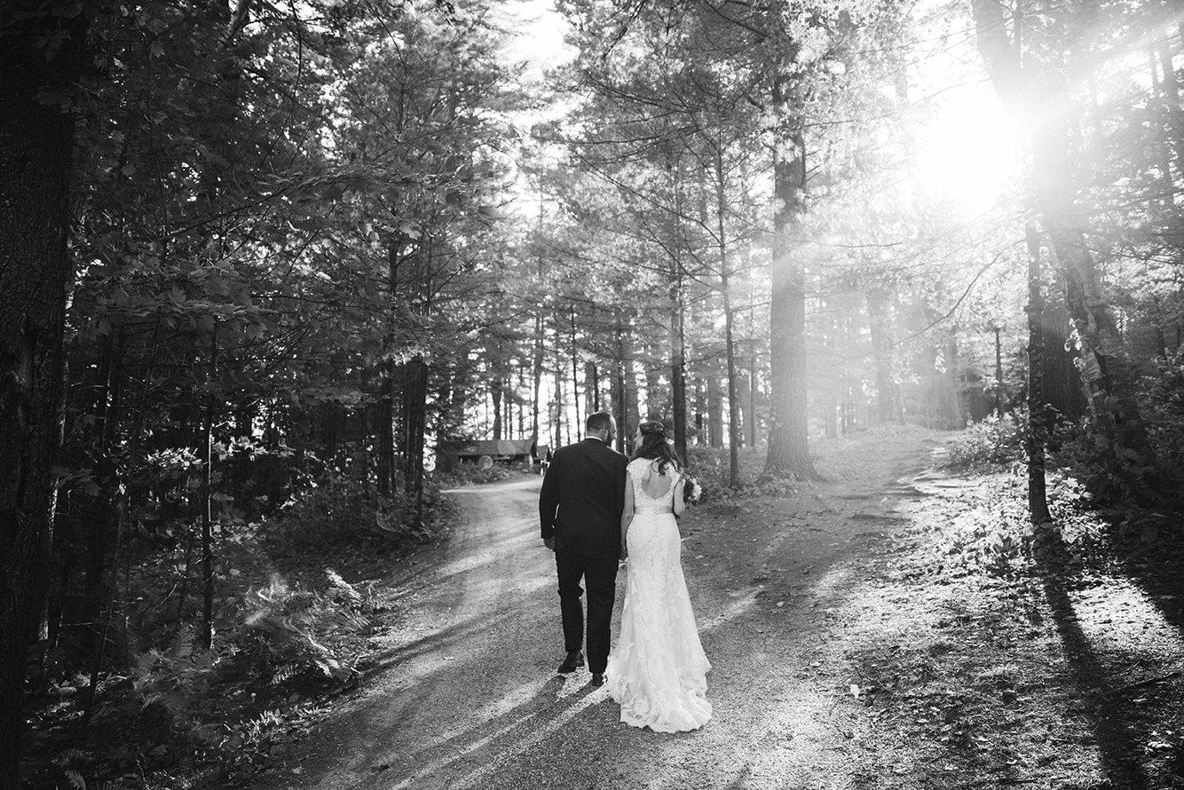 A natural portrait of a bride and groom walking in the woods during their Kingsley Pines Camp Wedding in Maine