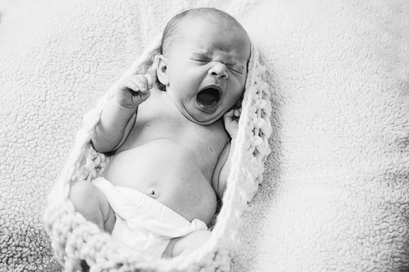 A portrait of a baby girl yawning during an in home newborn session in the Jamaica Plain neighbourhood of Boston, Massachusetts