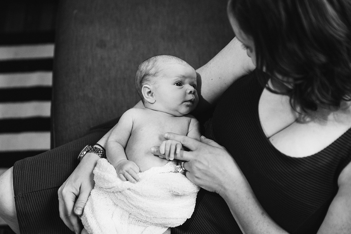 A lifestyle photograph of a mother holding her new baby girl during an in home newborn session in the Jamaica Plain neighbourhood of Boston, Massachusetts