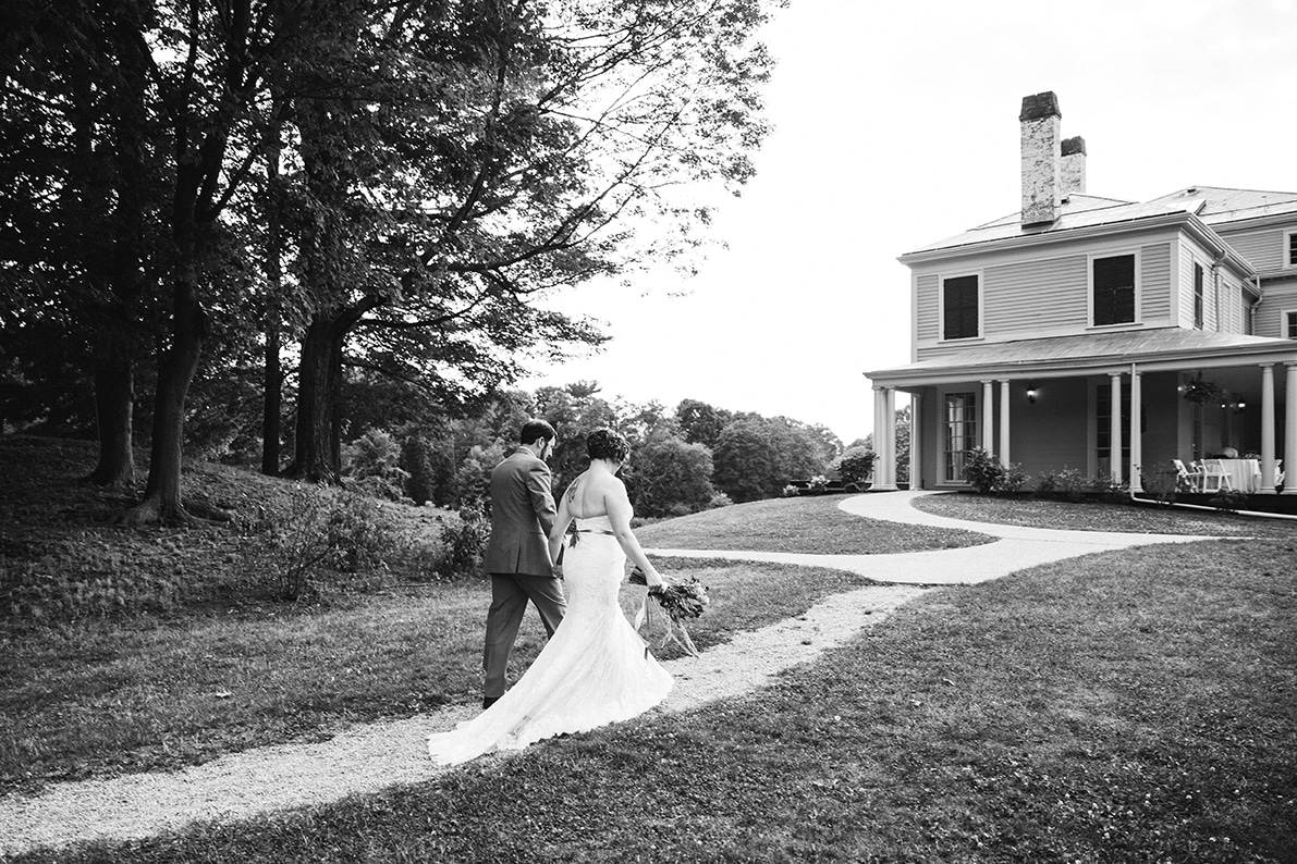 A documentary photograph of a bride and groom walking to their cocktail hour during a Lyman Estate Wedding in Boston, Massachusetts