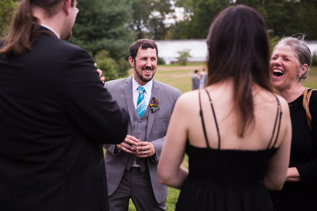 A documentary photograph of guests talking and laughing at a Lyman Estate Wedding in Boston, Massachusetts