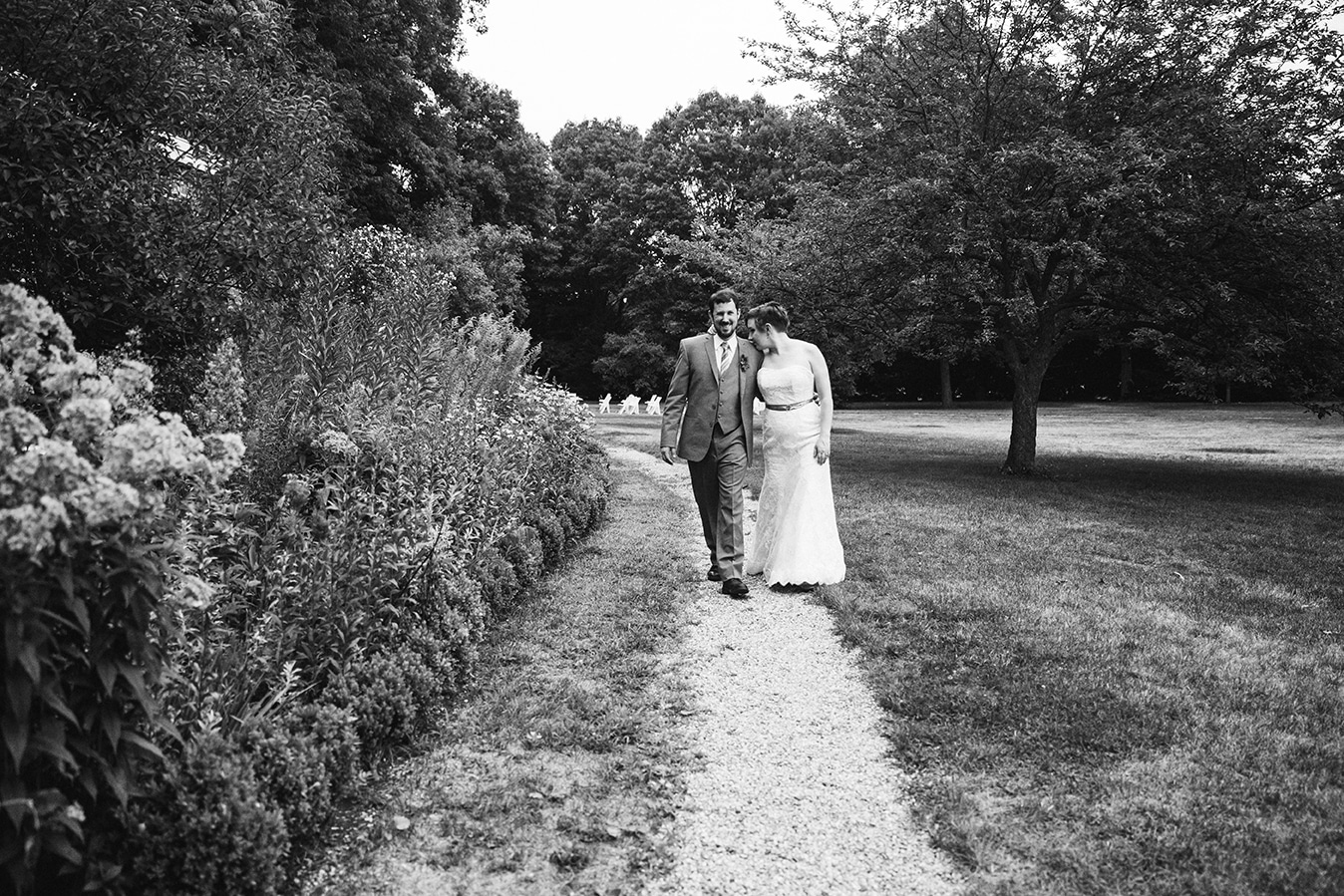 A documentary photograph of a bride and groom walking to the reception of their Lyman Estate Wedding in Boston, Massachusetts
