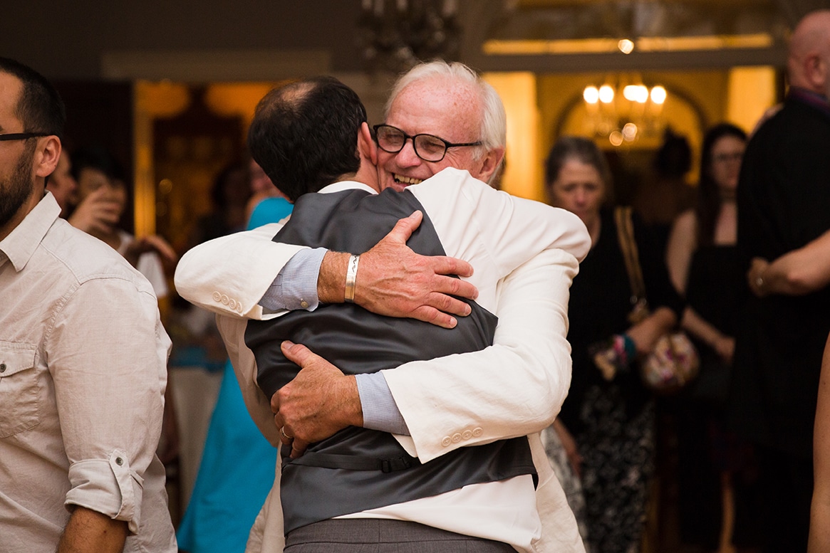 A documentary photograph of a Groom hugging his father during a Lyman Estate Wedding in Boston, Massachusetts