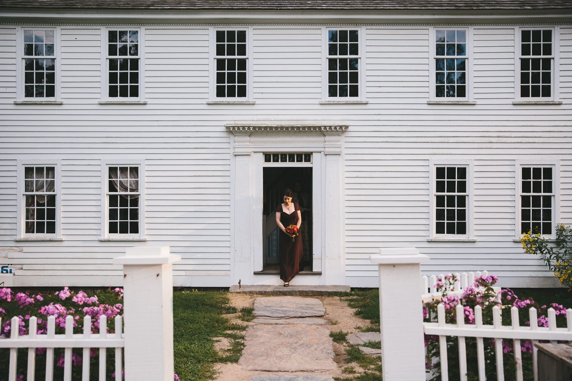 This documentary photograph of a bridesmaid walking out of the house is one of the best wedding photographs of 2016