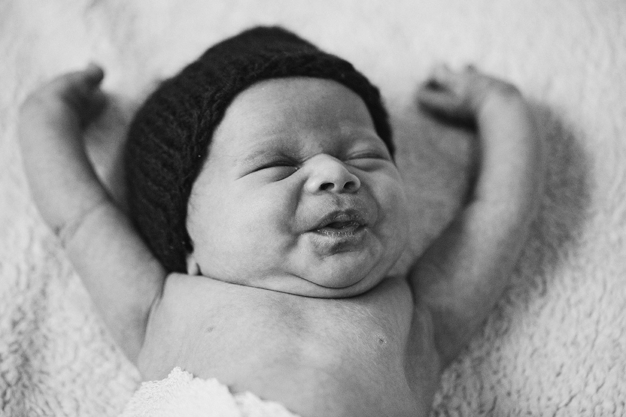 This lifestyle portrait of a newborn stretching her arms is one of the best family photographs of 2016