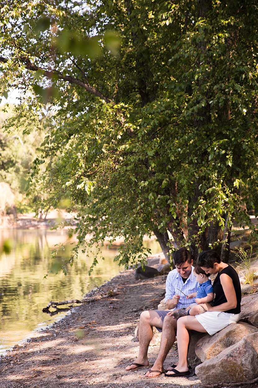 A lifestyle portrait of a family sitting together on rocks during a Jamaica Pond Family Session in Boston, Massachusetts