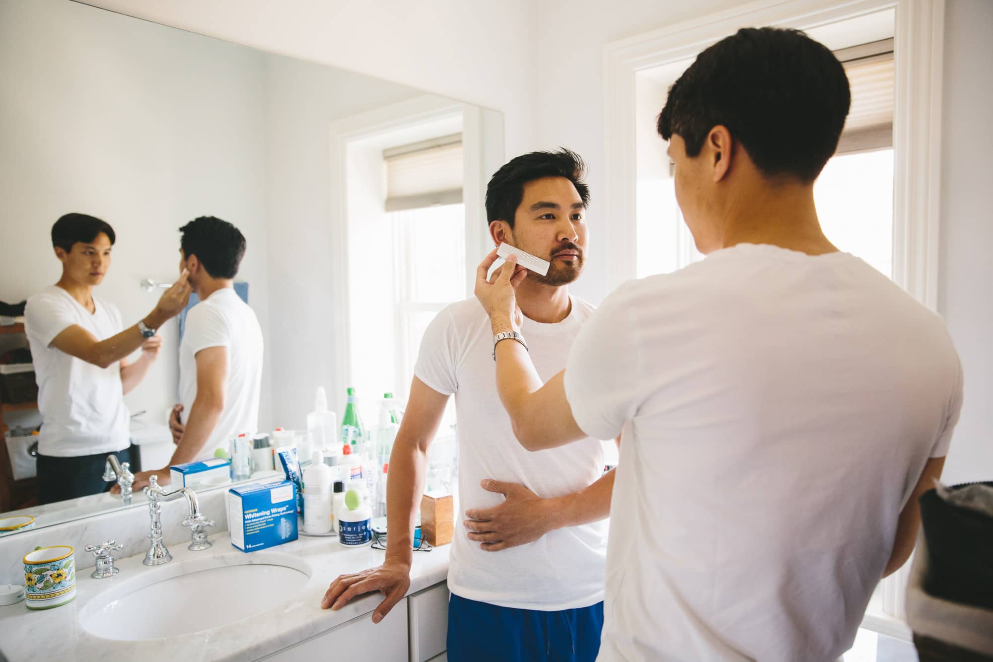 A documentary photograph of a groomsmen helping the groom shave before his Artists for Humanity Wedding in Boston, Massachusetts
