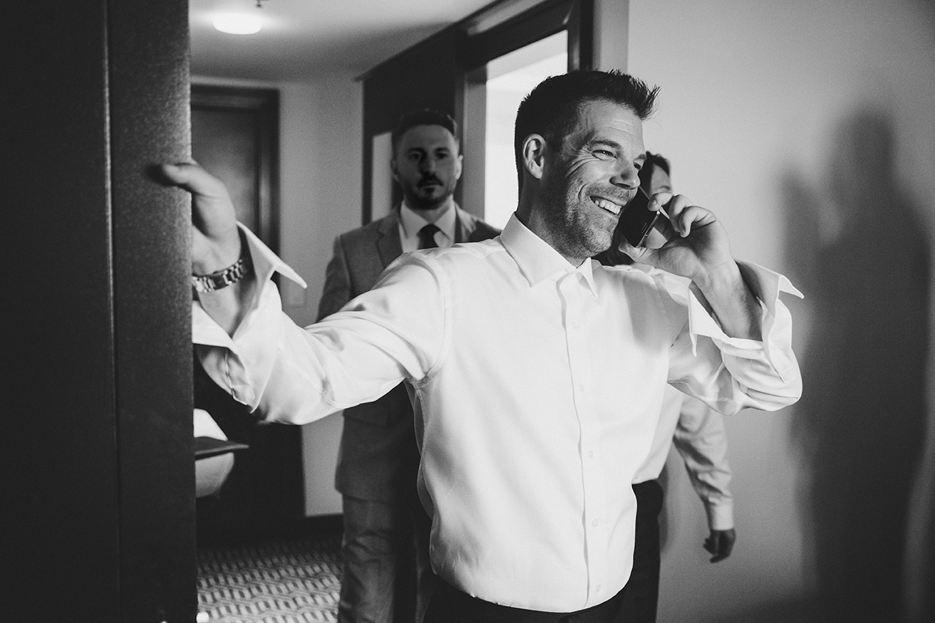 A documentary photograph of a groom talking to his bride on the phone before their old south meeting house and marliave wedding in Boston, Massachusetts