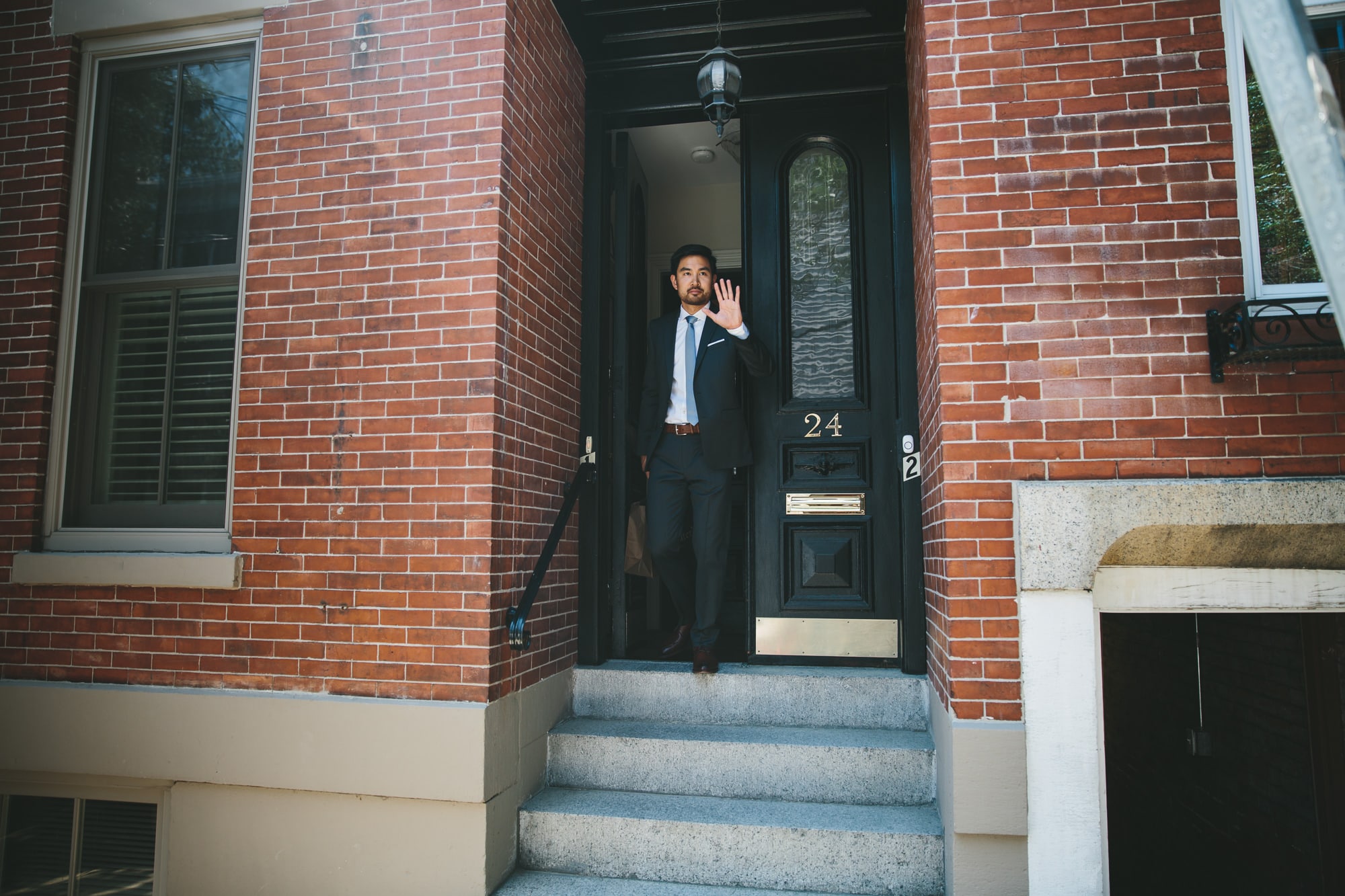 A documentary photograph of a groom waving to his uber driver before his Artists for Humanity Wedding in Boston, Massachusetts
