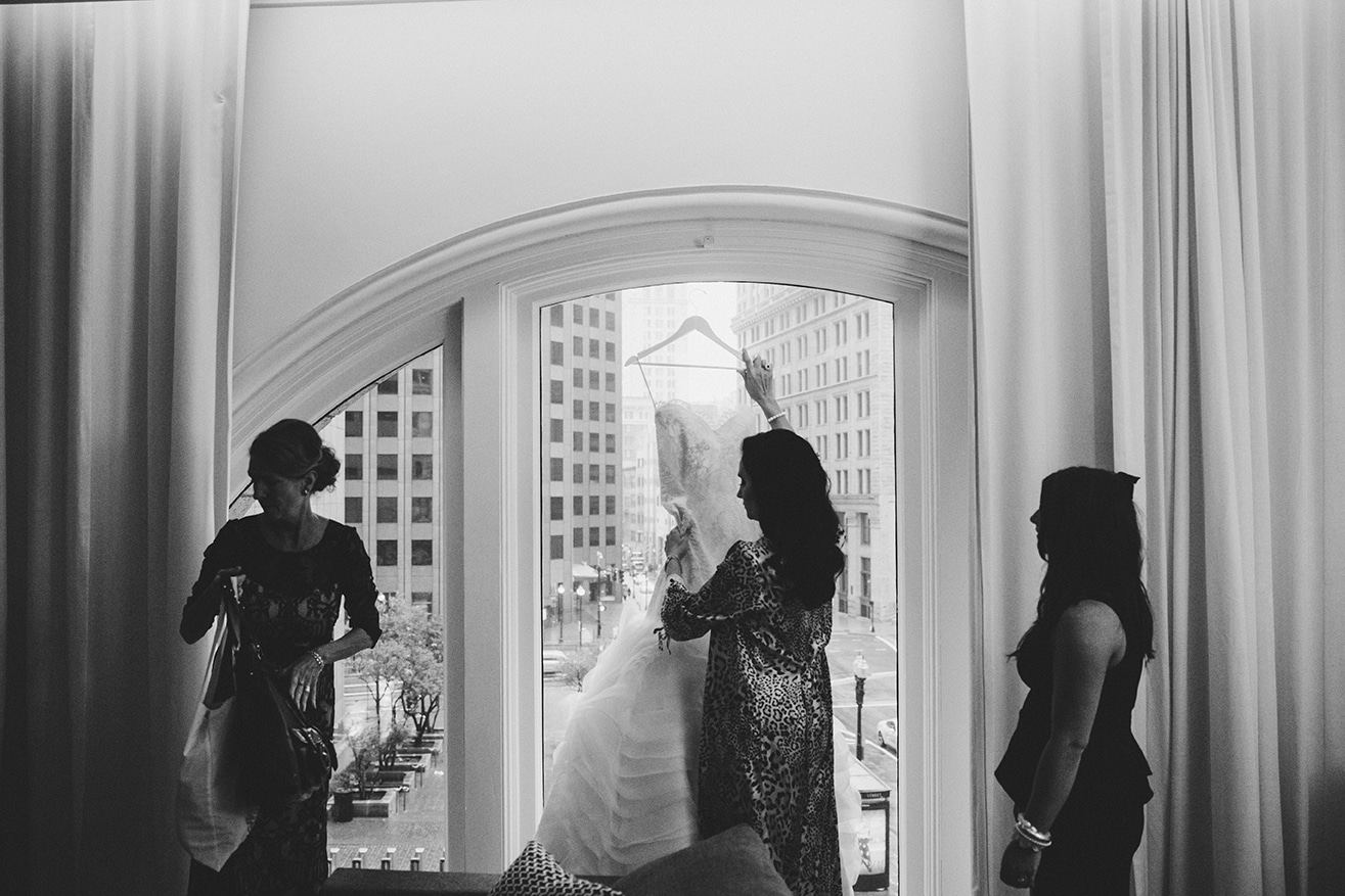 A documentary photograph of a bride taking down her wedding dress before her old south meeting house and marliave wedding in Boston, Massachusetts
