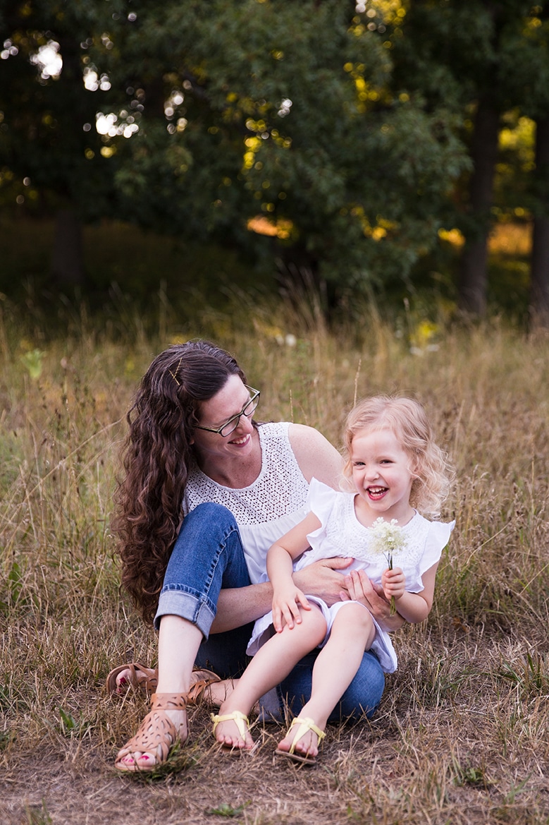 A documentary photograph of a mom laughing with her daughter during their Arnold Arboretum Family Session in Boston, Massachusetts