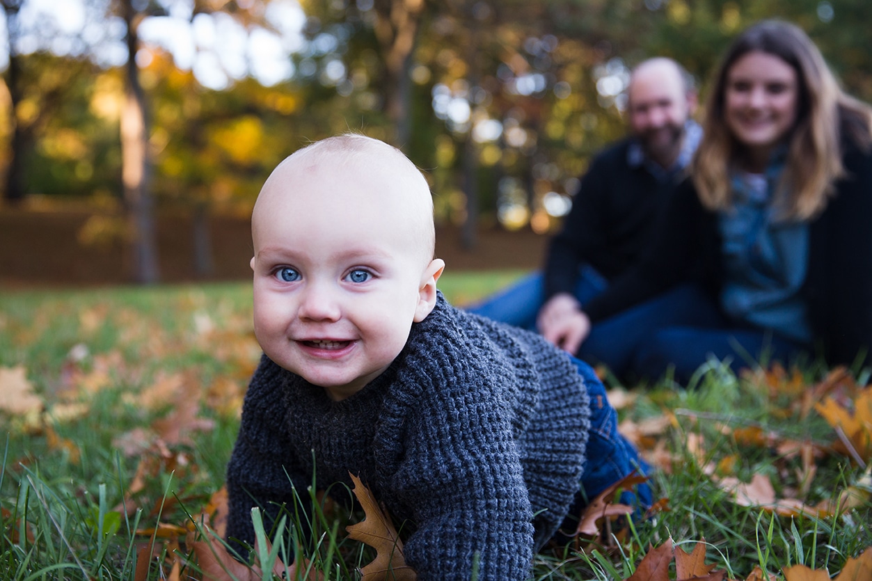 A documentary photograph of a baby crawling in the Arnold Arboretum during a lifestyle photo session in Boston, Massachusetts