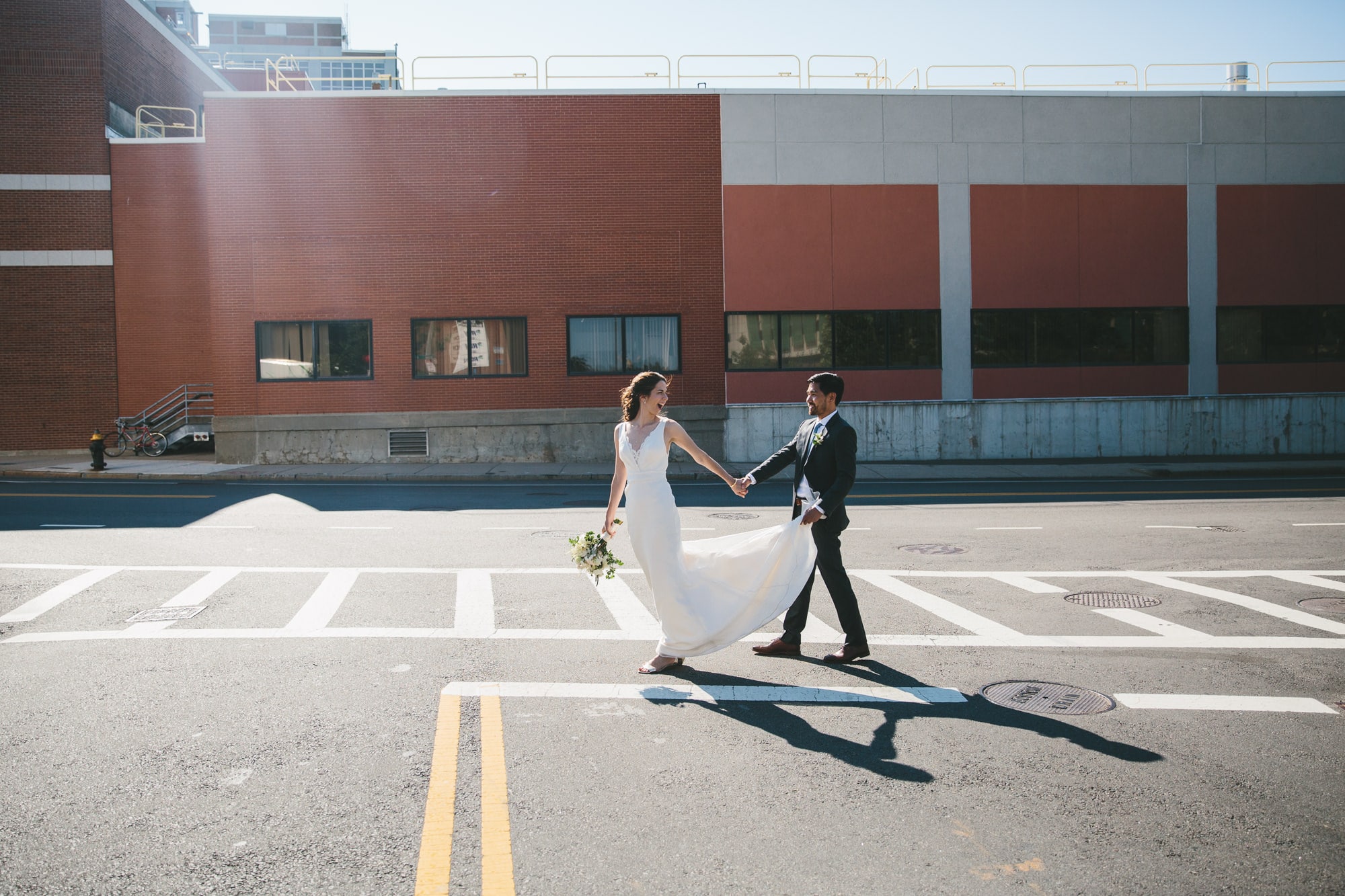 A documentary photograph of bride and groom crossing on the street before their Artists for Humanity Wedding in Boston, Massachusetts