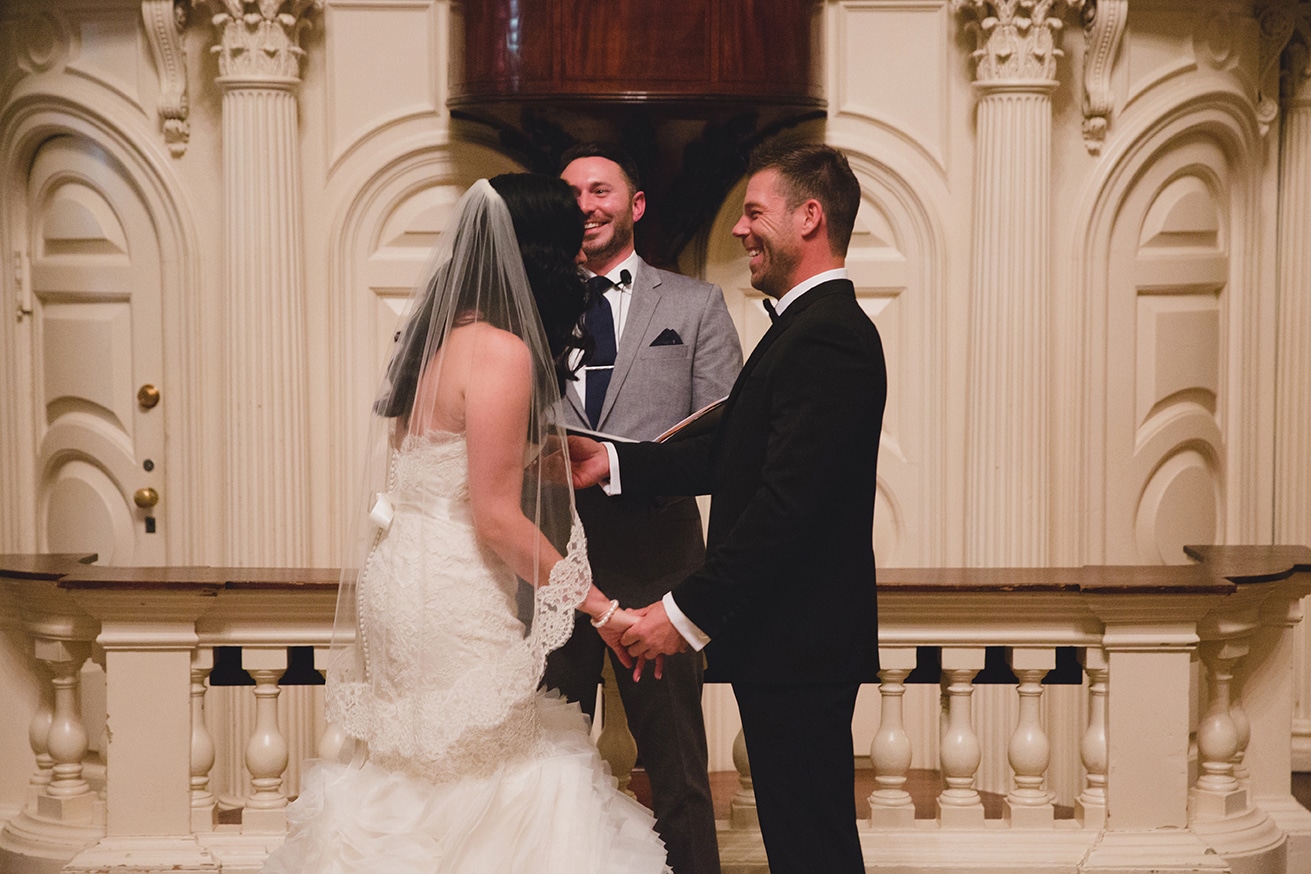 A documentary photograph of a bride and groom laughing during their wedding ceremony at the old south meeting house in Boston, Massachusetts