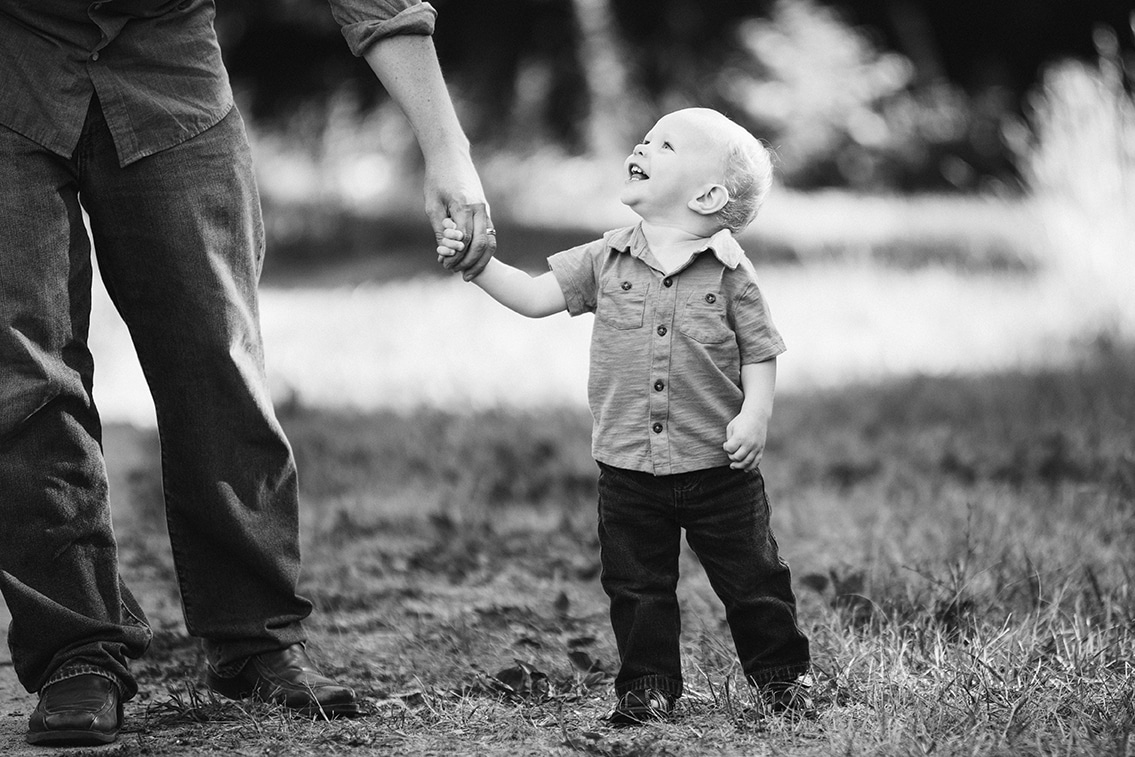 A documentary photograph of a little boy holding his father's hand during their Arnold Arboretum Family Session in Boston, Massachusetts