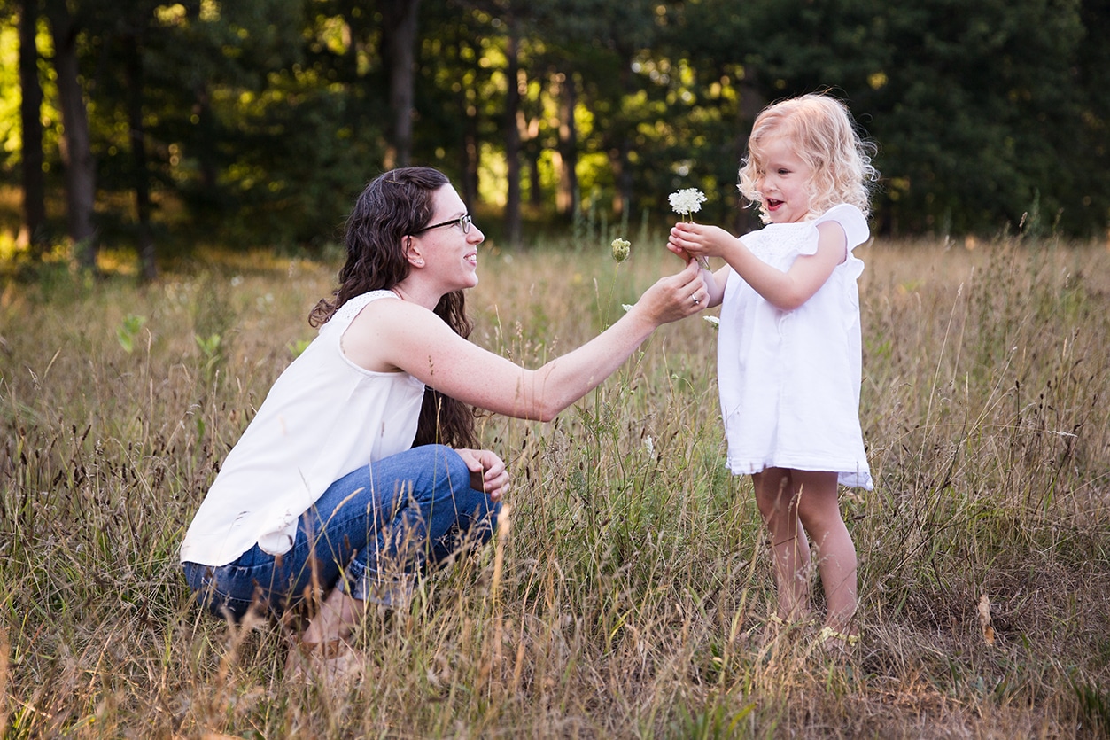 A documentary photograph of a mom giving her daughter a flower during their Arnold Arboretum Family Session in Boston, Massachusetts