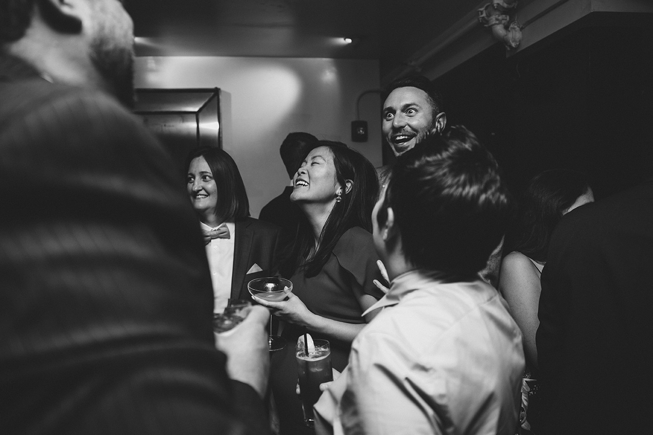 A documentary photograph of guests talking and laughing during a marliave wedding reception in Boston, Massachusetts